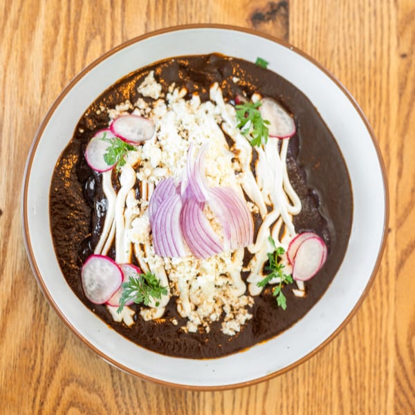Polanquito's mole poblano, garnished with crumbled cheese, sour cream, red onion, radishes, and cilantro.