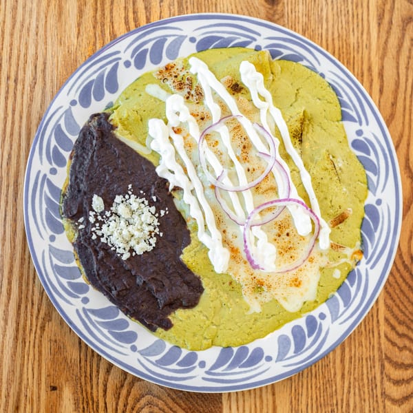 Polanquito's green enchiladas with black beans, sour cream, red onion, and crumbled cheese.