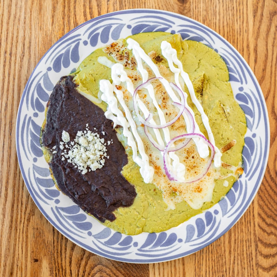 Polanquito's green enchiladas with black beans, sour cream, red onion, and crumbled cheese.