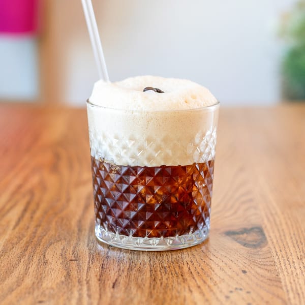A Polanquito Mexican coffee drink with foam and a coffee bean on a wooden table.
