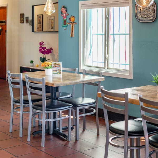Polanquito restaurant interior with wooden tables, metal chairs, and a bright window with colorful streamers.