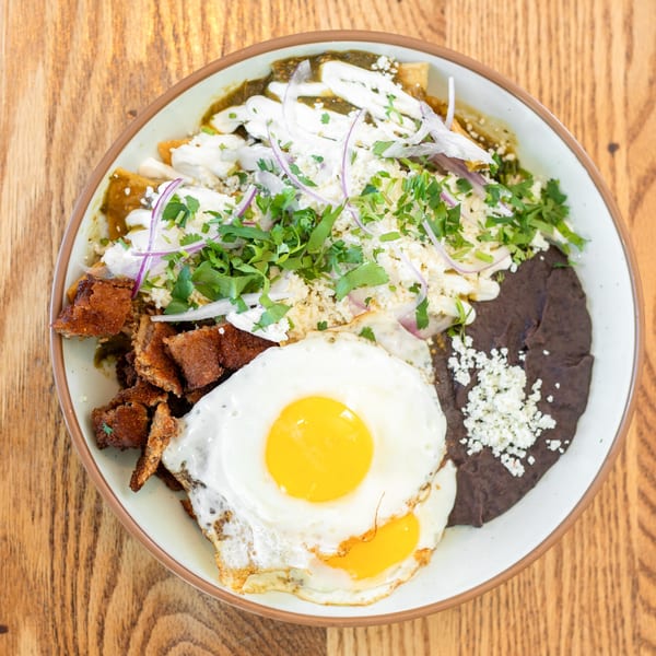 Polanquito's chilaquiles with green salsa, fried eggs, black beans, carnitas, and fresh toppings.